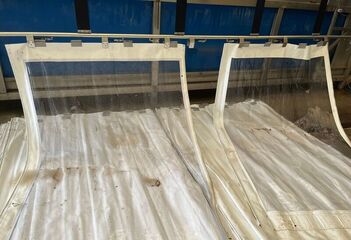 Verschmutzte Seitenplanen werden in die Waschanlage aufgehangen.